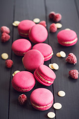 Raspberry macaroons on black wooden background