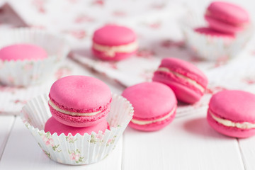 Pink raspberry macaroons on white wooden background