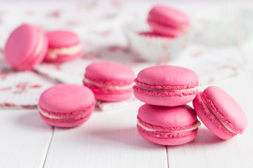 Pink raspberry macaroons on white wooden background