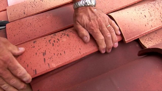 Le couvreur pose la derni&egrave;re tuile sur son chantier