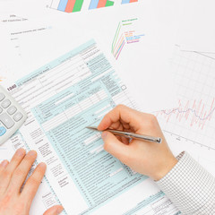 Male filling out 1040 US Tax Form with silver pen - indoors shot
