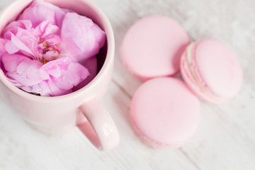 Obraz na płótnie Canvas Tea cup with rose and macaroons, selective focus