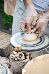 The hands of a potter help the child make a pitcher on a pottery