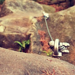 Detail of steel bolt anchor eye in rock. The end knot  of steel rope. Climbers path in rocks via ferrata. Iron twisted rope fixed in block.