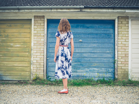 Young woman in dress standing outside garage