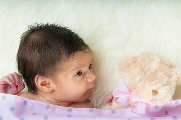 Niña bebé recién nacida feliz tranquila relajada con su peluche sobre una manta de pelo