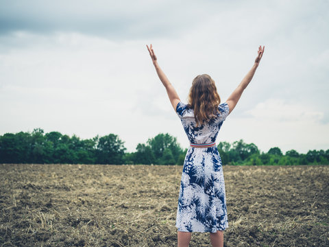 Woman raising her arms in barren field