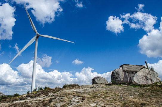 Windrad neben Granitsteinhaus (Casa do Penedo)