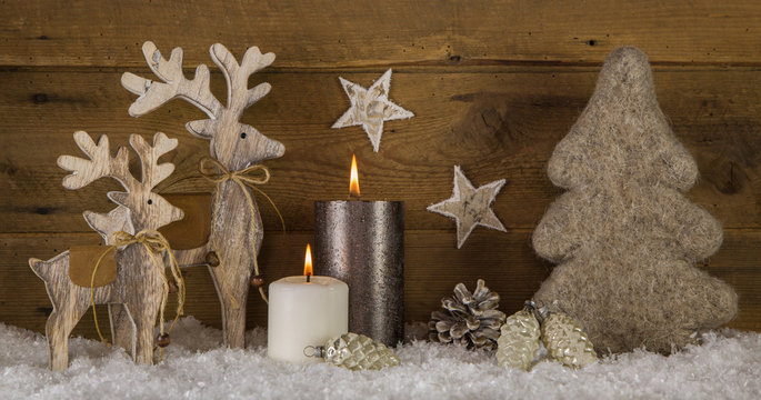 Zweiter Advent. Zwei brennende Kerzen mit natürlicher Dekoration zu Weihnachten in weiß braun.