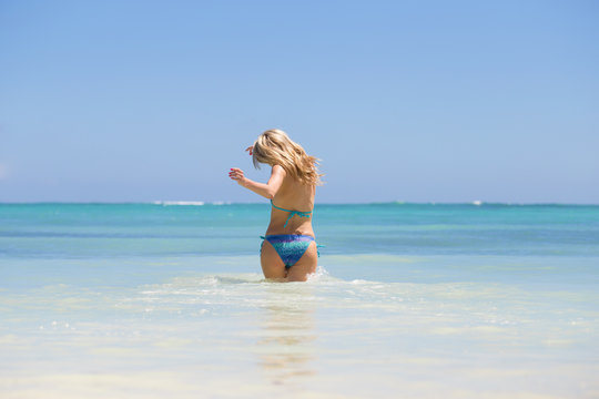 Cheerful woman running into water