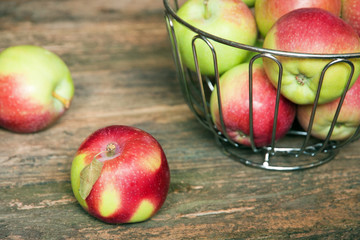 Apples in a metal basket on a wooden table.