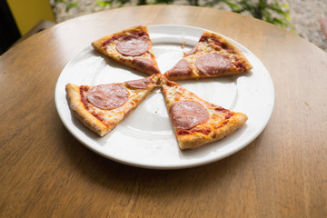 sliced salami pizza on a white plate
