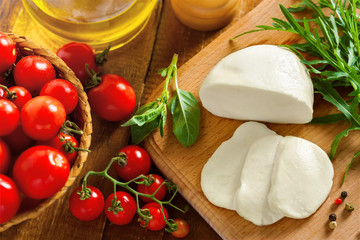 Sliced mozzarella, tomatoes and arugula on table, top view