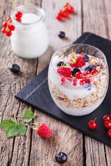 Breakfast with muesli, yogurt,honey and fresh berries in a glass on a wooden background. selective focus