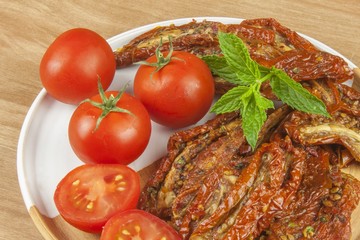 Spicy dried tomatoes marinated in olive oil. Delicious delicacy. Refreshments at the party. Sun-dried tomatoes with olive oil, background. Healthy food.
