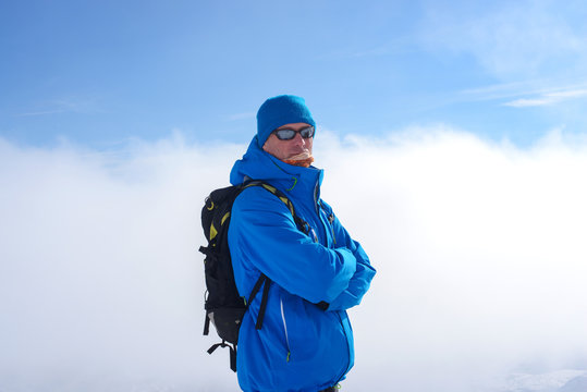 Man with backpack wearing sunglasses is standing in mountains in