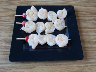 Shrimp skewers served on a black plate.