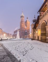 Naklejka premium Krakow, Poland, St Mary's church and Sukiennice (Cloth hall) on the Main Market Square in heavy snow