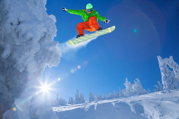 Snowboarder jumping against blue sky