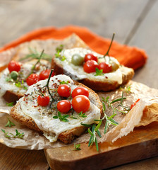 Fototapeta na wymiar Bruschetta with cheese, cherry tomatoes and aromatic herbs