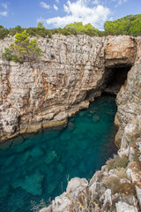 Fototapeta na wymiar Empty sea cave, shallow water and steep and rugged cliff at the Lokrum Island in Croatia.