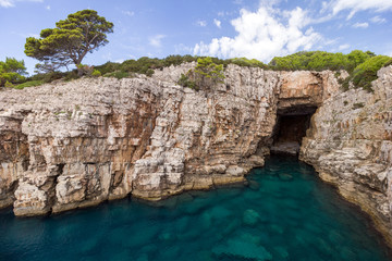 Fototapeta premium Empty sea cave, shallow water and steep and rugged cliff at the Lokrum Island in Croatia.