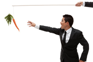 Businessman reaching for a carrot at the end of a stick