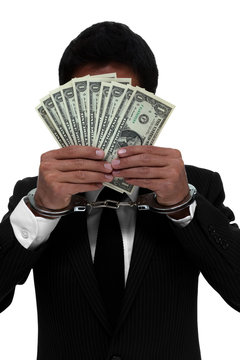 Businessman in handcuffs holding money in front of his face