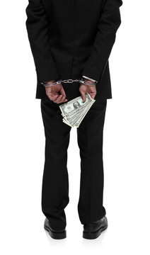 Dirty Businessman in handcuffs holding money behind his back