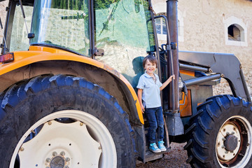 Portrait of little smiling boy in tractor in summe