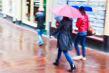 Menschen unterwegs in der regnerischen Stadt in Bewegungsunschärfe