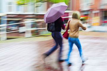Menschen unterwegs in der regnerischen Stadt in Bewegungsunschärfe