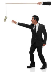 Excited businessman reaching for money on the end of a stick