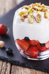Vanilla mousse with strawberries, blueberries and pistachios in a glass beaker.selective focus
