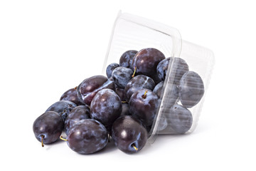 Box or punnet and spilled fresh ripe organic plums isolated on white background