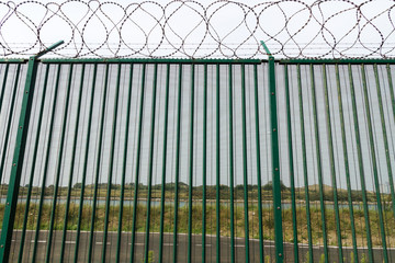 Green fence with razor wire guarding French ferry terminal.