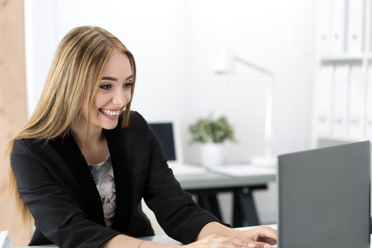 Young smiling business woman working at laptop in the office