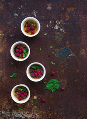 Creme brulees with raspberries and mint in white bowls over