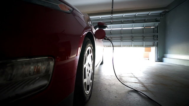 electric vehicle charges in garage - dramatic angle