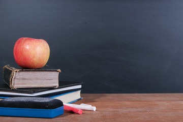 Apple, Books and Chalks with Blackboard Background