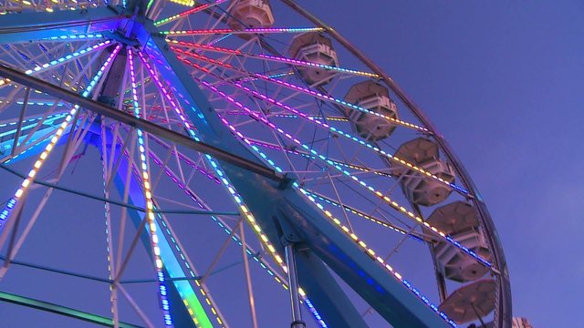 A ferris wheel spins and is brightly lit.