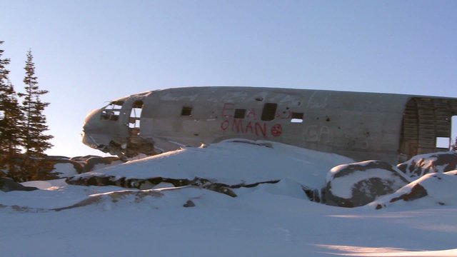 A crashed plane sits on a frozen snowy mountainside in the Arctic.