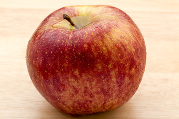 Red apple with water drops on a wooden background