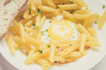 Fried eggs with penne pasta and ciabatta