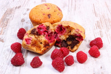 Fresh baked muffins with chocolate and raspberries on wooden background, delicious dessert