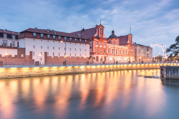 Obraz premium Odra river waterfront in Wroclaw, Poland, with Ossolineum museum and library and university building, in early morning, seen from Sand Island (Wyspa Piasek)