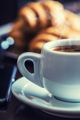 Coffee break business. Cup of coffee mobile phone croissants and newspaper.