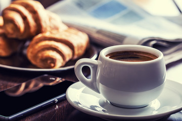 Coffee break business. Cup of coffee mobile phone croissants and newspaper.