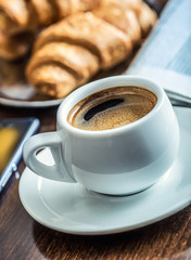 Coffee break business. Cup of coffee mobile phone croissants and newspaper.