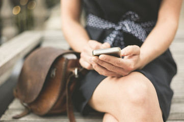 Obraz premium Young woman on bench in city with phone